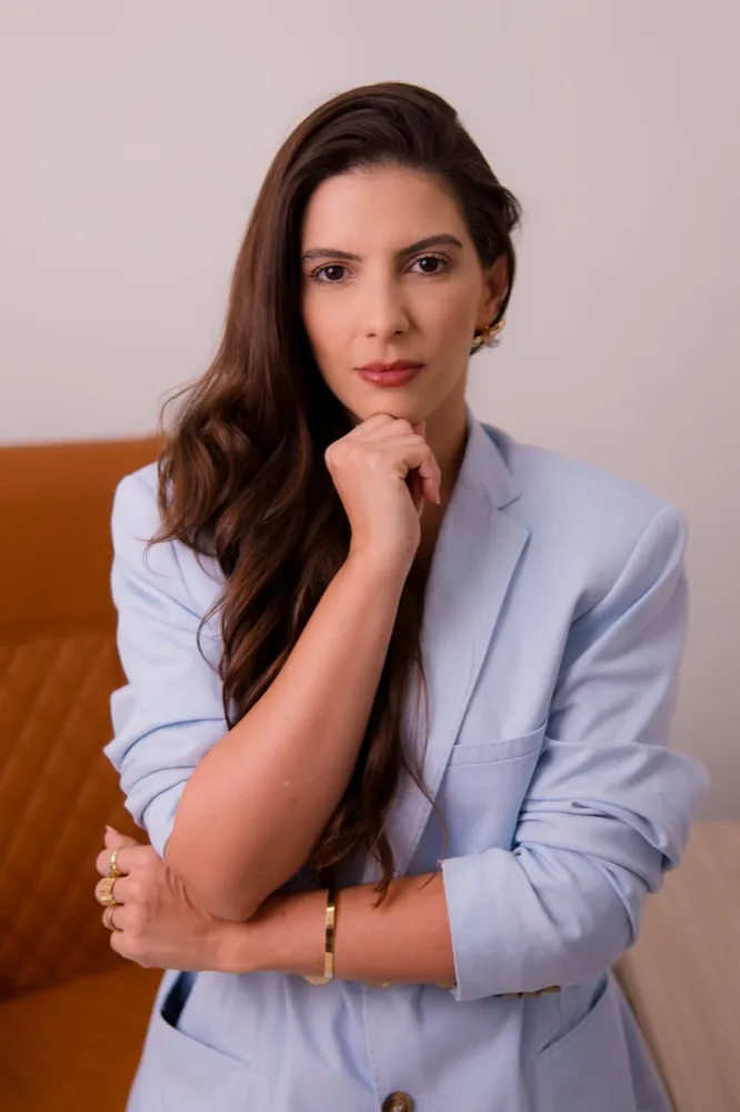 Dra. Kattia Rogério de braços cruzados na poltrona do consultório