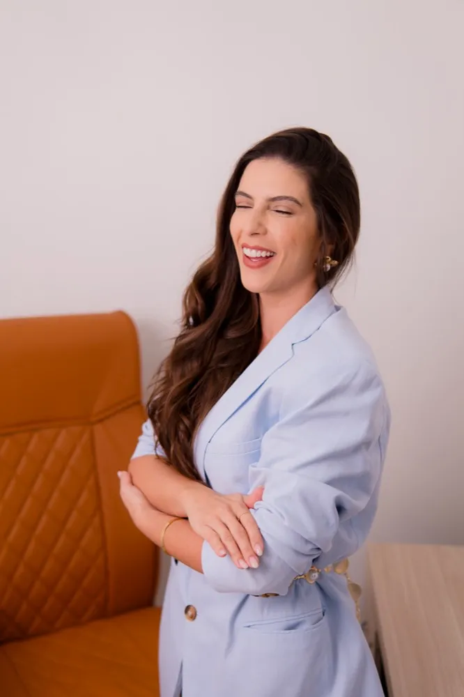 Dra. Kattia Rogério rindo, de braços cruzados